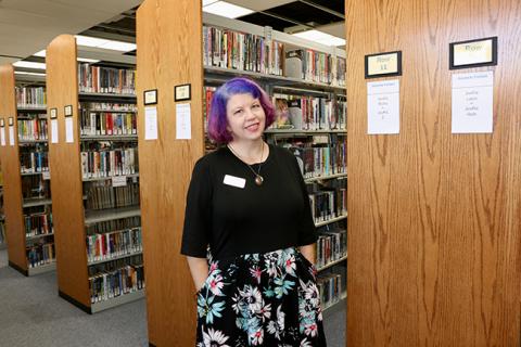 A woman standing in front of library shelves.