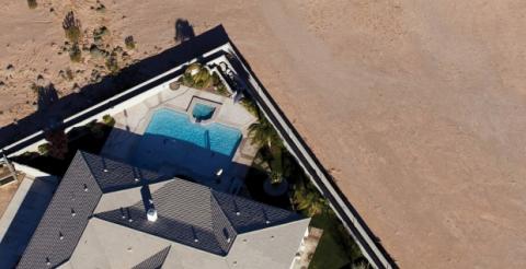 Aerial view of house with pool in backyard with nothing behind the house but dirt.