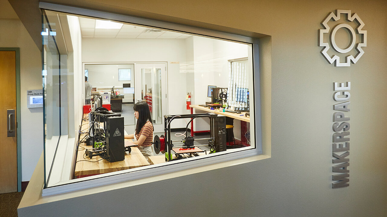 Looking through interior window to interactive makerspace equipment