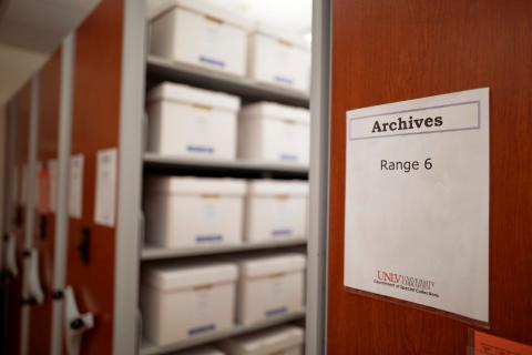 Looking down rows of collapsible archive shelves. Text on closest end cap shows, "Archives, range 6."