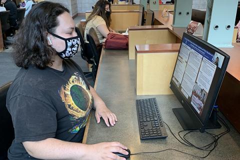 Student sitting at computer desk in library for remote class