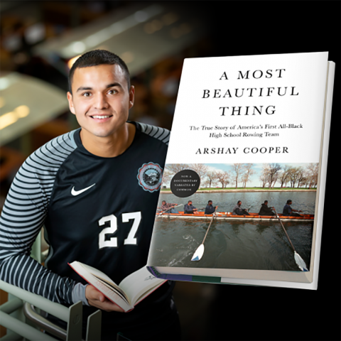 Student athlete posing with open book; book cover of A Most Beautiful Thing displayed in foreground