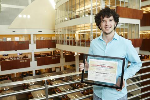 Man in light blue shirt holding framer certificate