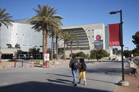 Two people walk toward the front entrance of a building.