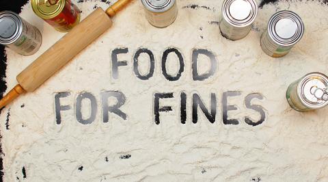 "Food For Fines" spelled out in flour with canned food and a rolling pin. 