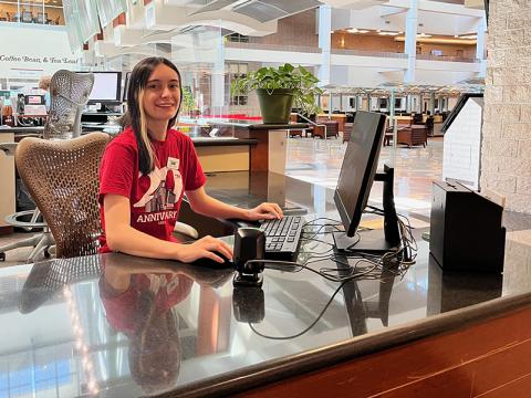 A student sits at a computer at the Circulation Desk in Lied Library.