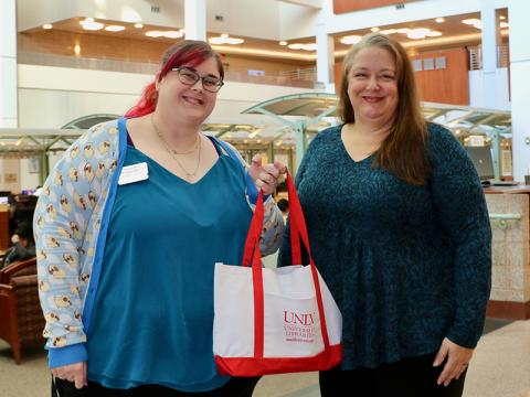 Two people holding a white and red canvas bag