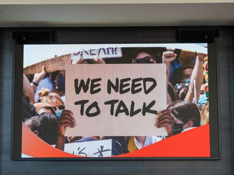 Image of the We Need To Talk logo on a TV screen. 