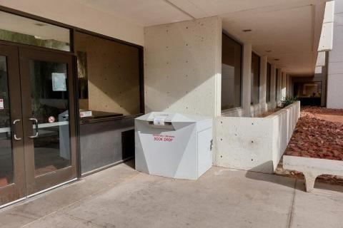 Large white library drop box located adjacent to the south entrance of the Carlson Education Building.