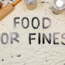 "Food For Fines" spelled out in flour with canned food and a rolling pin. 