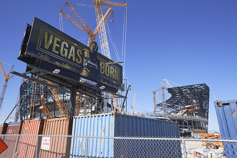 A billboard advertising the Vegas Golden Knights Hockey team looms over the Allegiant Stadium construction site.