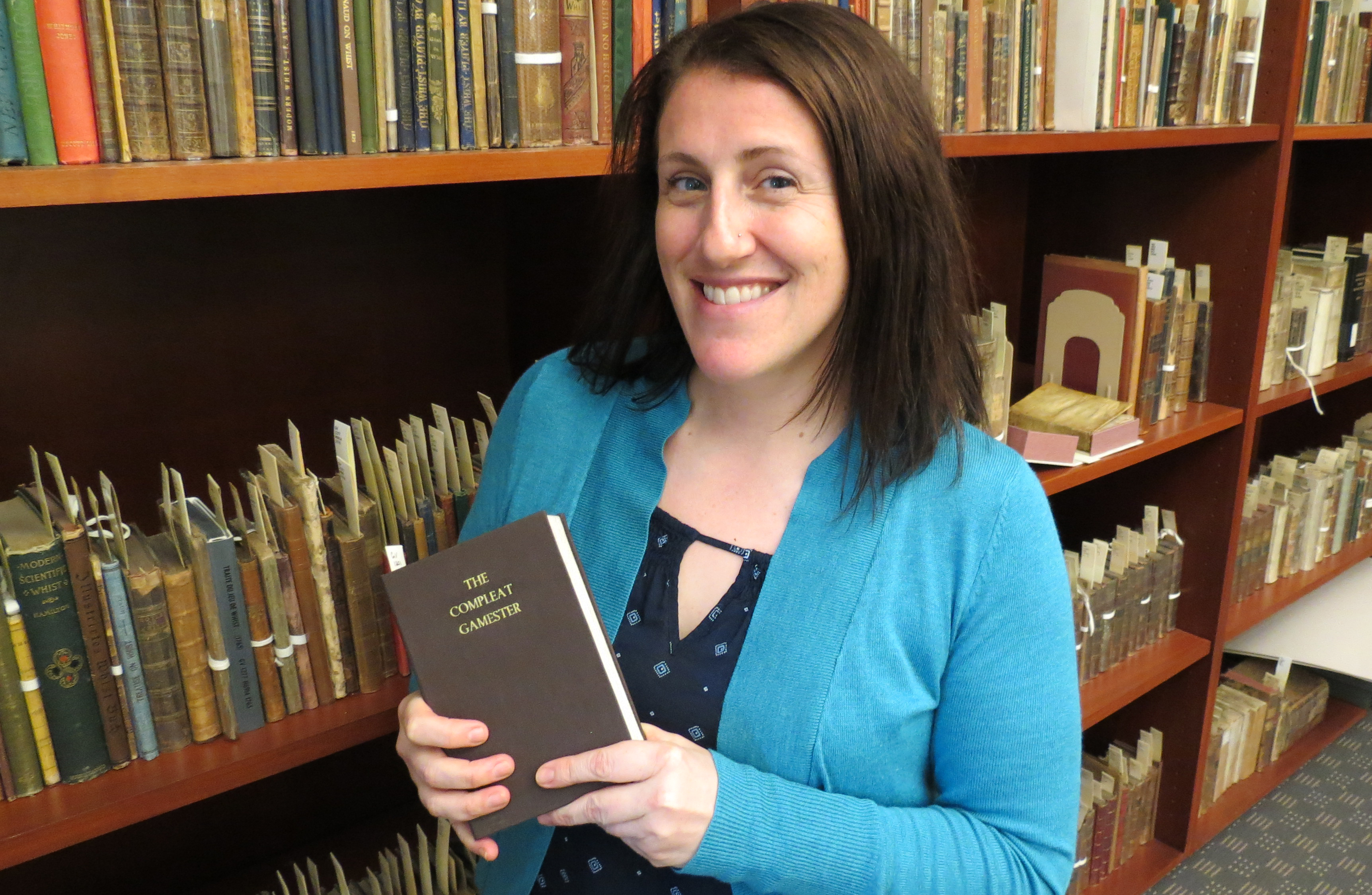 Dr. Celeste Chamberland holds a copy of The Compleat Gamster from the historical gaming collection in UNLV Special Collections.
