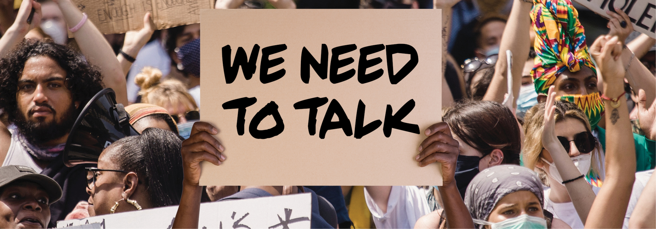 Crowd clapping with someone holding up a sign that shows, "We need to talk"