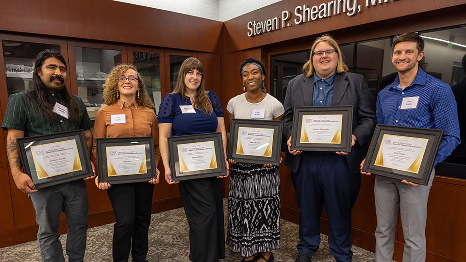 Six people holding award certificates.