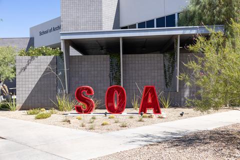 Red "SOA" letters in front of a modern building labeled "School of Architecture."