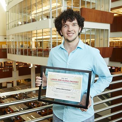 Man in light blue shirt holding framer certificate