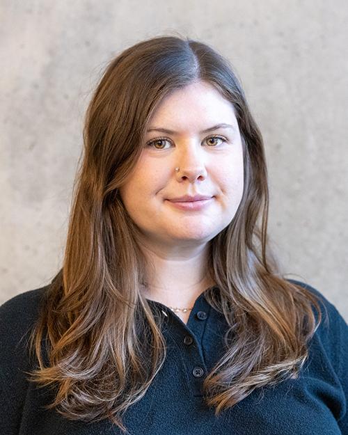 Chelsea Kai Roesch standing in front of a cement wall.