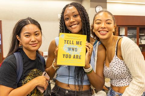 Three people holding a book.