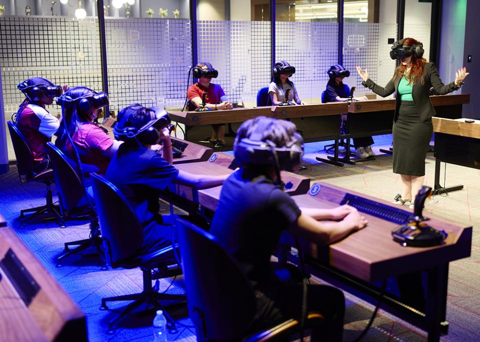 A classroom with students wearing VR headsets seated at desks, facing an instructor.