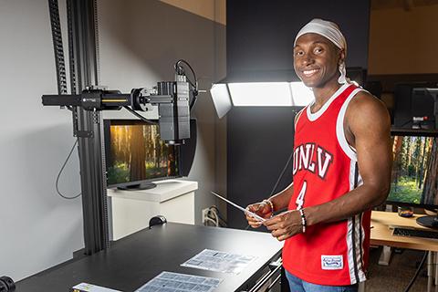 Person in a red "UNLV" jersey standing next to scanning equipment in a studio setting.