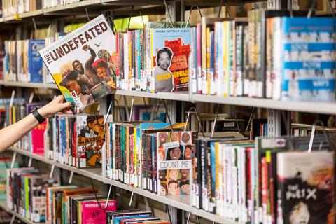 A hand pulls a book off a bookshelf. 