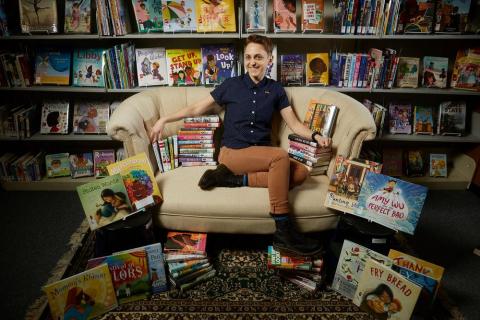 Amanda Melilli sitting on a chair surrounded by diverse books