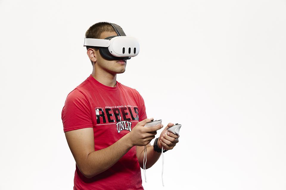 UNLV student wearing a VR headset and holding controllers.