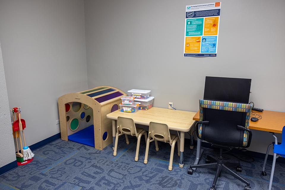 A play and study area with a play tunnel, child-sized furniture, and a computer workstation.