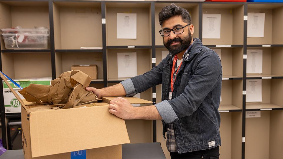 A student assistant unpacks a box in the Lied Library mailroom.