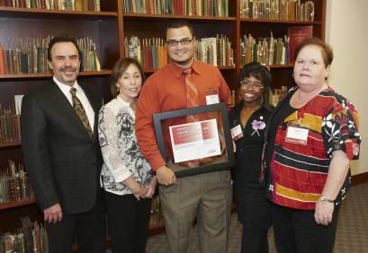 Group photo of Lance and Elena Calvert with 2009 award winner holding framed award certificate