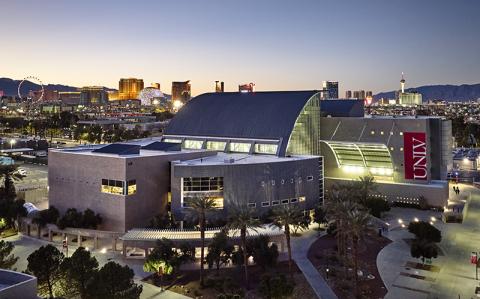 Aerial view of a modern building at sunset with the Las Vegas skyline in the background.