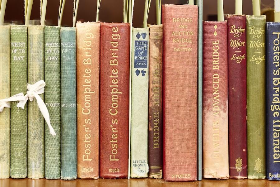 A row of vintage books on Whist and Bridge games with colorful spines.