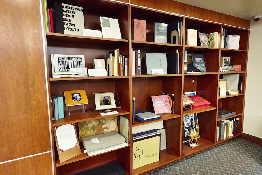 Wooden bookshelf filled with books and art objects.