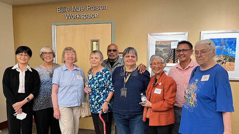 A group of nine people standing in front of the "Billie Mae Polson Workspace" door.