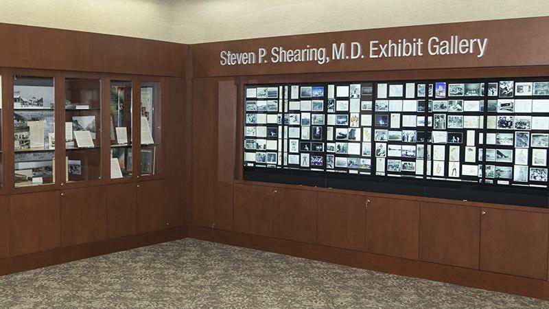 Steven P. Shearing, M.D. Exhibit Gallery with wooden display cases and a digital showcase of images.