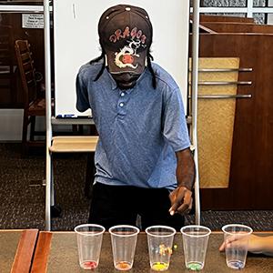 A person sorts colorful beads into plastic cups.