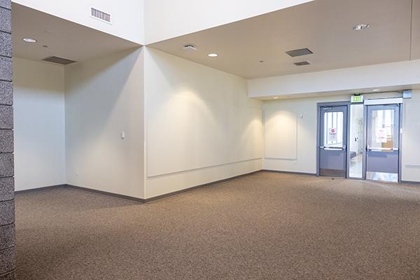 Empty second floor library gallery space with white walls and carpeted floor.