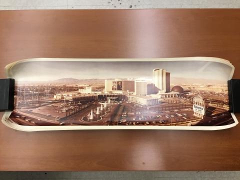 A wide exterior view of Caesars Palace in 1980. Across the front of the casino hangs two vertical portrait banners of Frank Sinatra. The Las Vegas valley can be seen in the background.