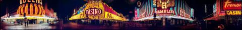 A panoramic view of the “4 corners” street viewpoint on Fremont Street in Las Vegas, Nevada, approximately 1979 to 1982. It is nighttime, and the front entrances and illuminated neon marquees for the Four Queens, Golden Nugget, Binion’s, and Hotel Fremont are visible.