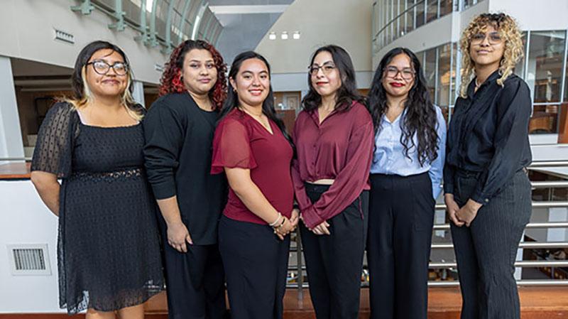 Six people standing indoors in formal attire.
