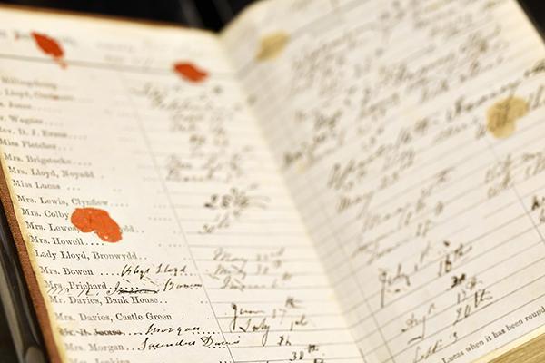 An open vintage ledger with handwritten entries, wax seals or stains, and neat cursive script.