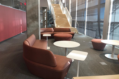 Cushioned seating and low tables and stairs in the bacground leading to the second floor of the library.