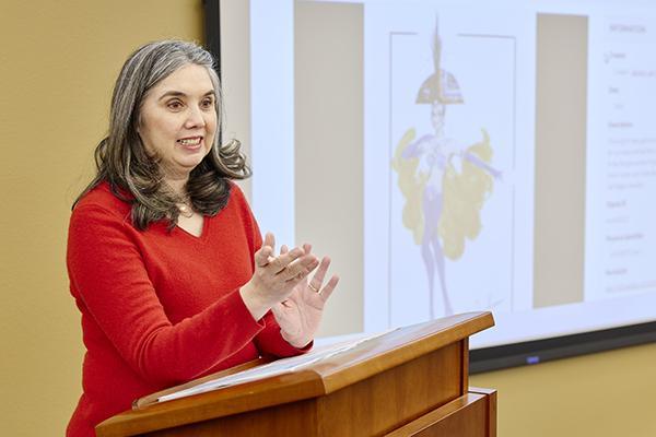 Woman presenting at a lectern with an image projected behind her.