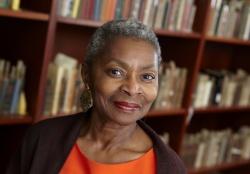 Claytee White, Founding Director of the Oral History Research Center standing in front of bookshelves.