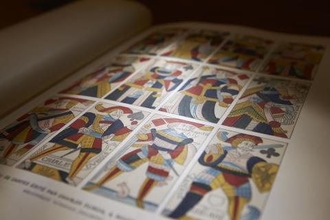 Close up of historical book page show colored drawing of cards from a deck