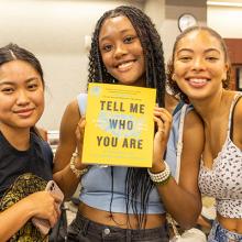 Three people holding a book.