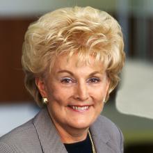 Smiling woman with short blonde hair in a grey blazer.