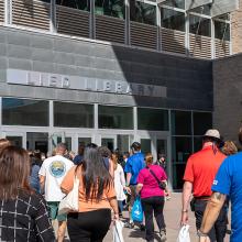 A group of people approaches the entrance of Lied Library, with a sign overhead.