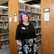 A woman standing in front of library shelves. 