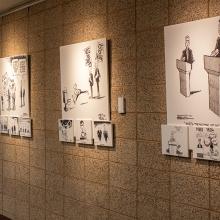 Wall-mounted display of black and white political cartoons in an indoor gallery.